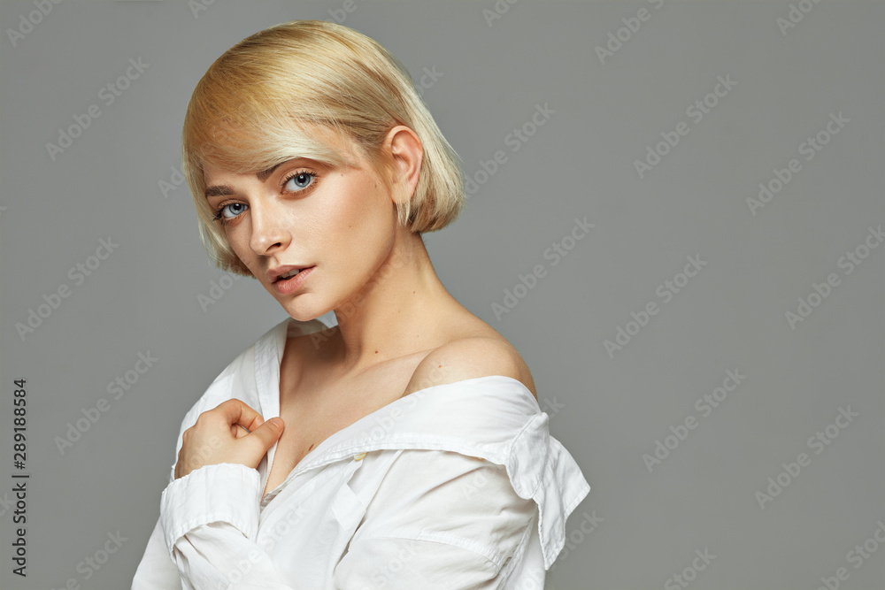 Portrait of blonde beautiful woman with short hair wear white shirt isolated on gray background Portrait of blonde beautiful woman with short hair wear white shirt isolated on gray background