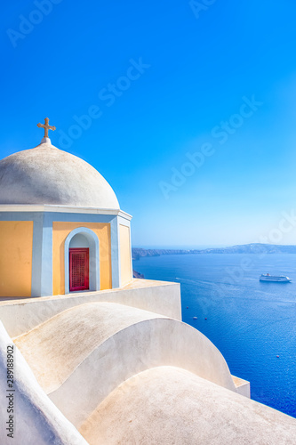 Greek Orthodox Church in Thira on Santorini Island with Line of Cruise Ships on Background.