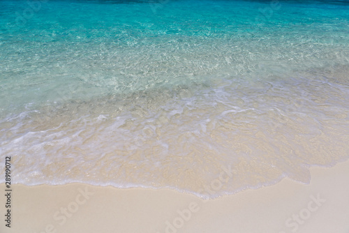 Ocean wave on a tropical paradise sandy beach. Beautiful surface texture, travel landscape clean white sand and blue turquoise sea water, wave ripple in beautiful ocean and natural sandy island.