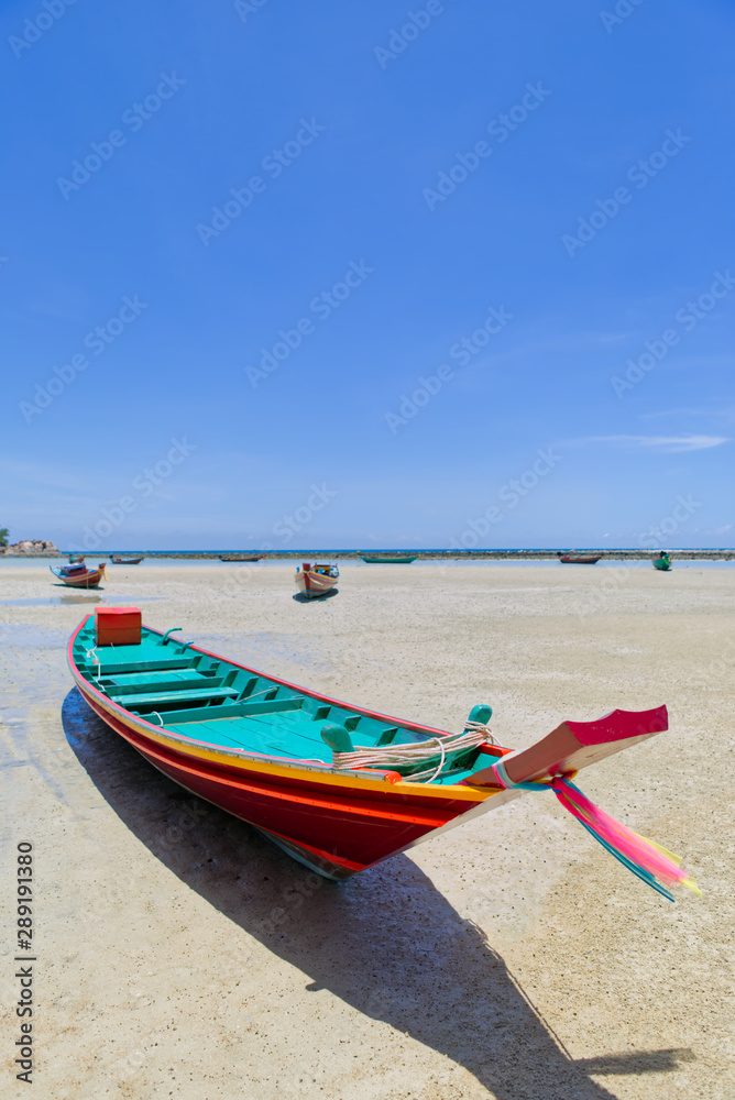 Colorful traditional long tail boat on the white sand beach at the low tide, in Phangan Island. Surat Thani, Gulf of Thailand