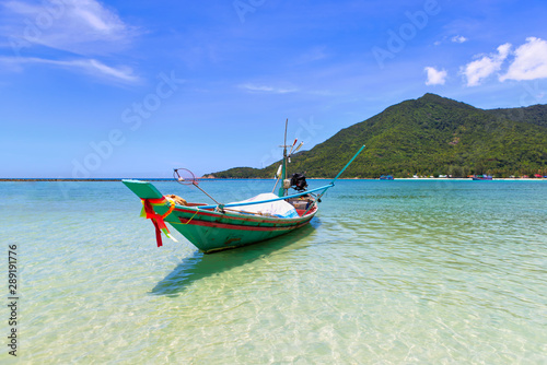 Colorful traditional long tail boat floating on tropical blue turquoise crystal clear water, white sand beach and lush green mountain at Chaloklum beach in Phangan Island. Surat Thani, Gulf ofThailand