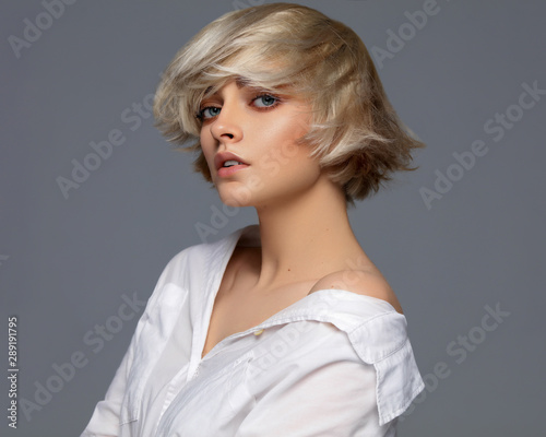 Portrait of beautiful blonde woman in white shirt and fashionable hairstyle