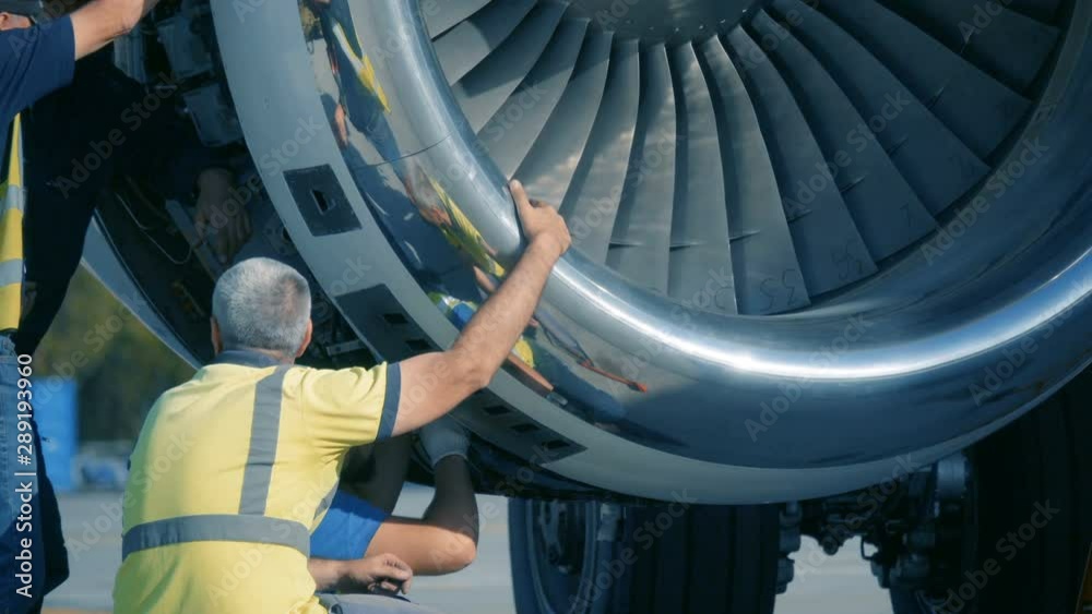 Aircraft Mechanics and Engineers  Diagnose and repairing jet engine through open hatch. Airplane turbine repair