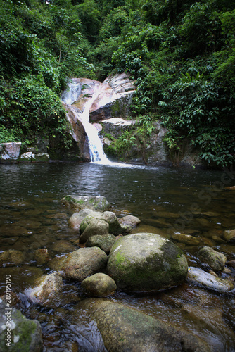Datfa waterfall. Stream of water fall to a little pond flowing through rocks and bolder in a lush green tropical jungle full of trees. Tai rom Yen National Park, Surat Thani, Thailand.