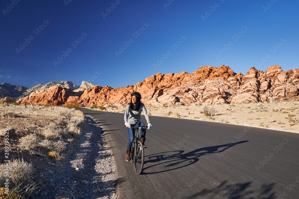 african american woman riding bicycle through red rock canyon park african american woman riding bicycle through red rock canyon park