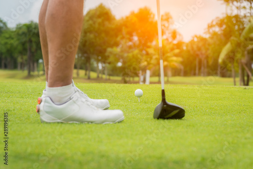 Golfer pushing white golf ball to hole at golf course in golf competition game , sunlight rays and blur background.