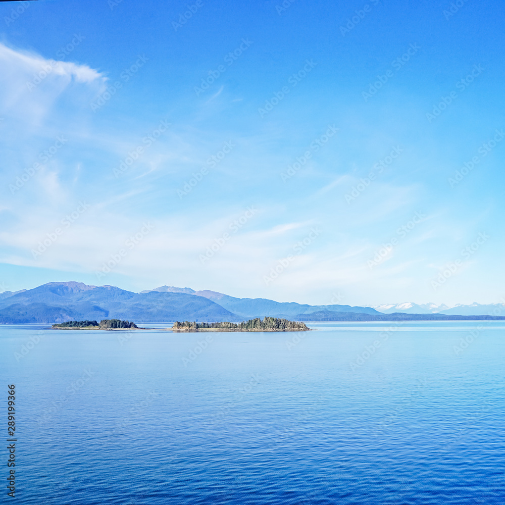 Sea stacks off the coast of Alaska with snow capped mountains in the background. Sea stacks off the coast of Alaska with snow capped mountains in the background.
