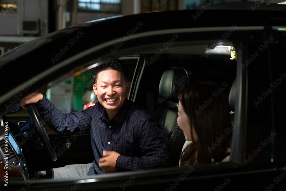 Obraz premium 夜の車の中で楽しそうに会話をする若い男女