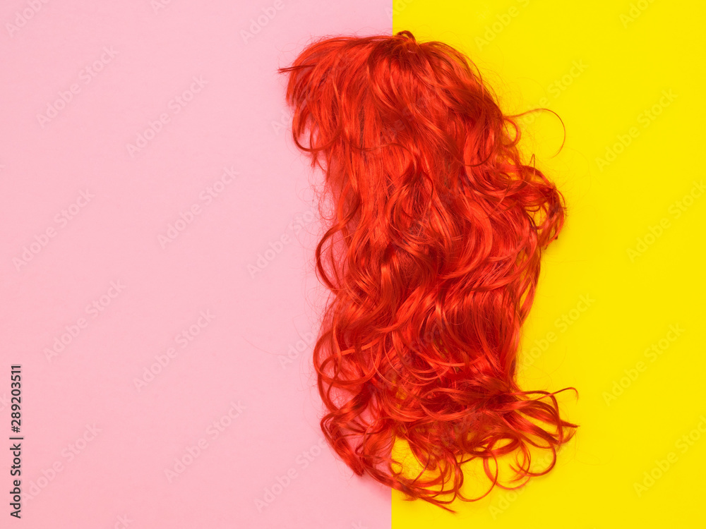 Bright orange wig on yellow and pink background. Accessories to create style.