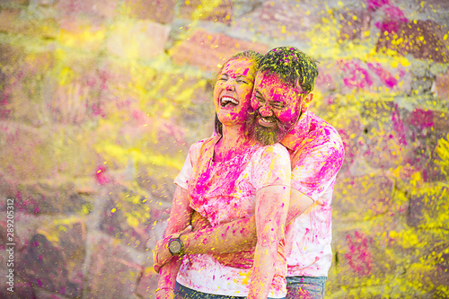 Cheerful Happy indian couple painted in colors celebrating holi festival having fun time outdoor, love and relationship copy space 
