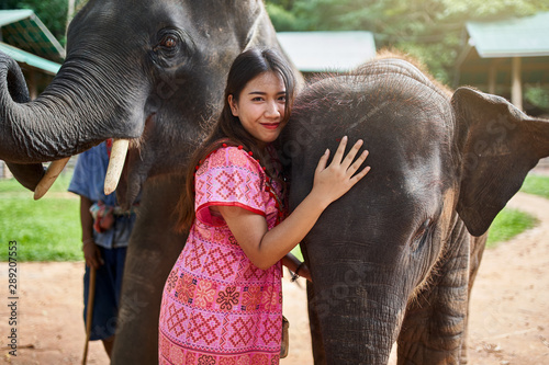 Fotografija female thai tourist having fun with baby and mother elephant at sanctuary in tha