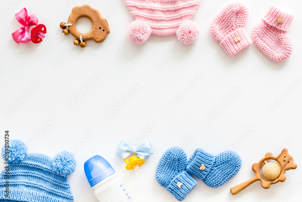 Blue and pink knitted set for kids, rattle, dummy, bottle frame on white background top view space for text - obrazy, fototapety, plakaty 