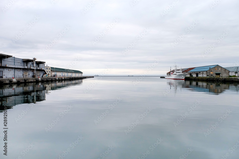 Harbor surrounding of fishing industry warehouse or fishery,boat is mooring on the bay floating on still water on white line skyin the port of Otaru sea on a background at Sapporo of Hokkaido in Japan