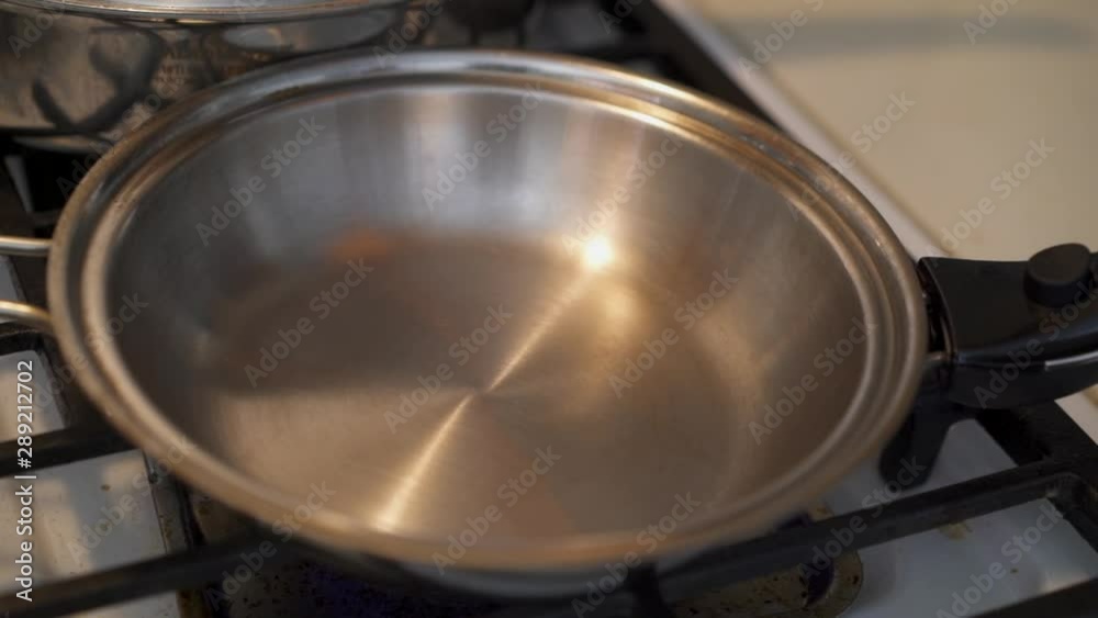 Cooking pan being placed on a gas stove burner Cooking pan being placed on a gas stove burner