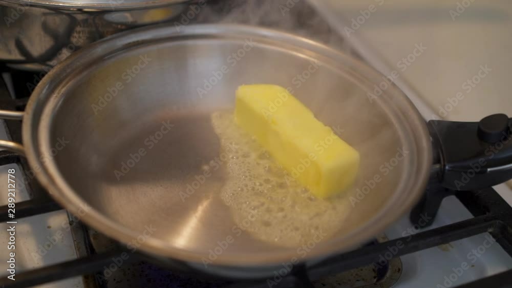 Putting a stick of butter in a hot pan on a gas stove burner Putting a stick of butter in a hot pan on a gas stove burner