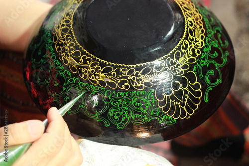 Canvas Print hands of a craftswoman painting decorative lacquer on traditional plates and bow