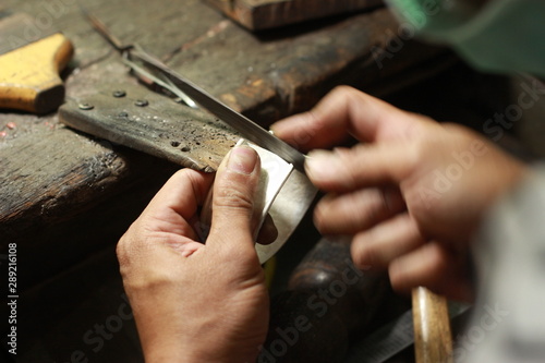 hands and tools of a professional silversmith working on a piece in his traditional workshop, Northern Thailand