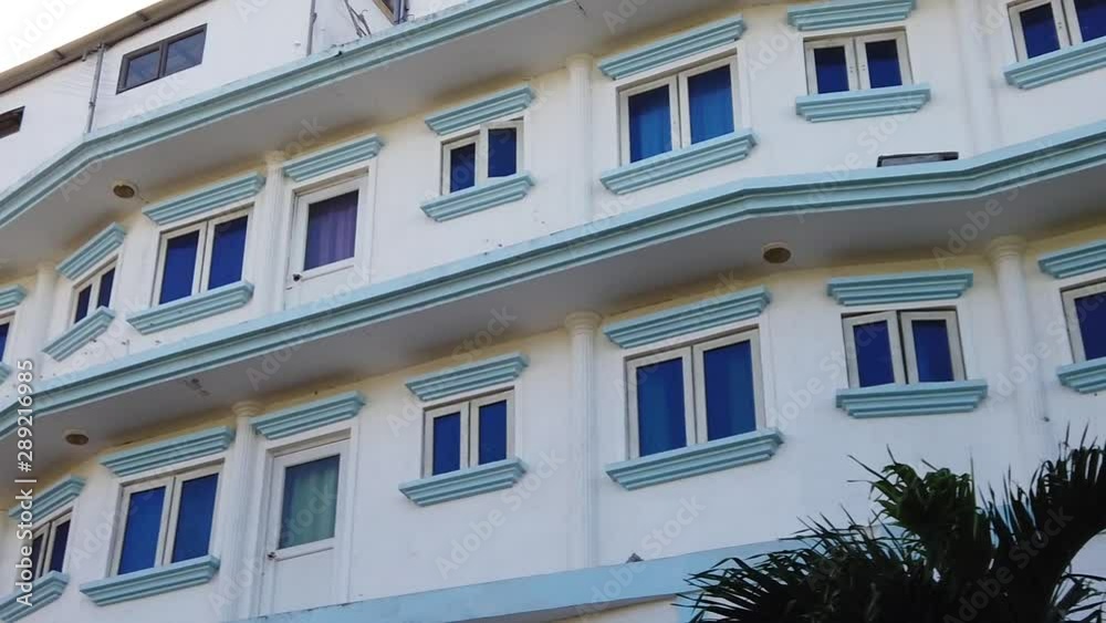 A shot of the facade of a colonial white house with blue windows. A shot of the facade of a colonial white house with blue windows.