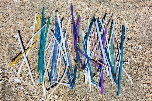 Heap of different multicolor plastic straws collected on the beach on sand background. Environmental pollution problem, say no plastic photo
