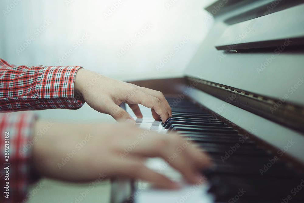 Fototapeta premium man hands is playing on piano keys with window light, Close up