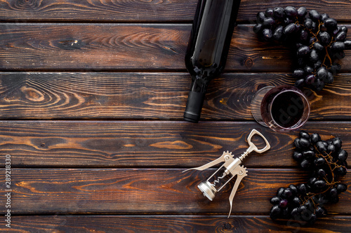 Red wine bottle near wineglass on dark wooden background top view copy space