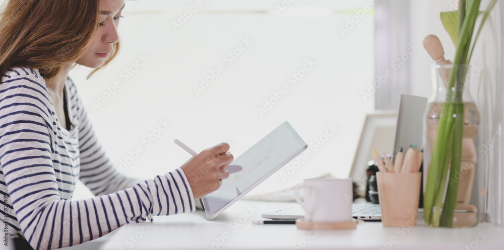 Professional young designer editing her project on tablet Professional young designer editing her project on tablet