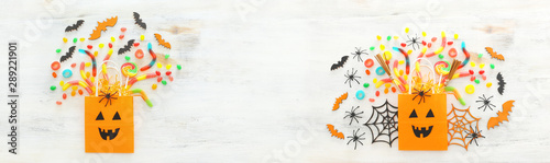 holidays image of Halloween. paper gift bag  spider  bats and sweets over wooden white table. top view  flat lay