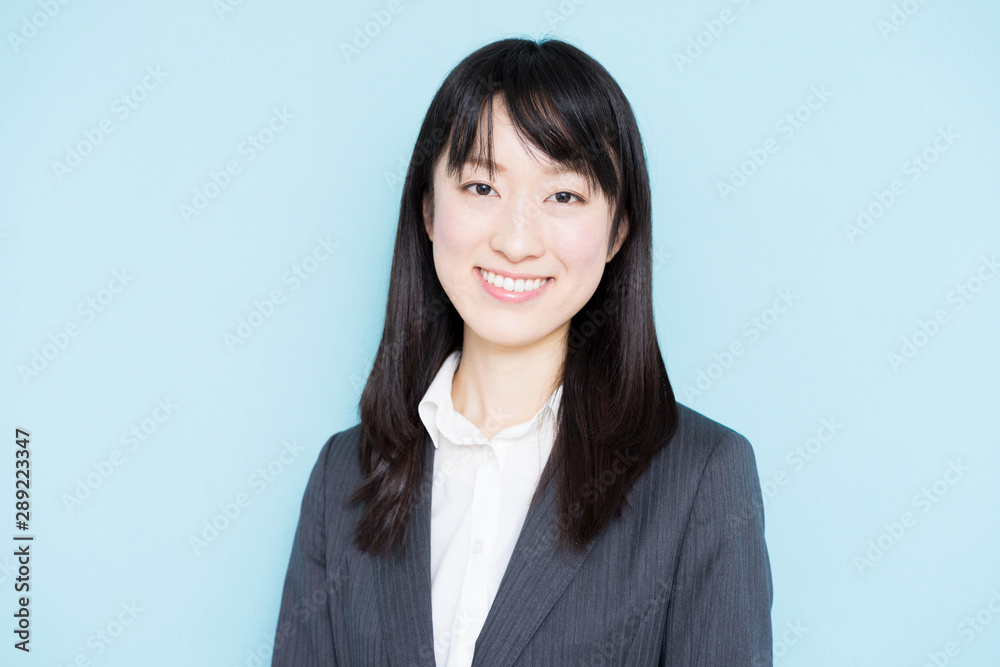 Young business woman wearing grey suit against light blue background Young business woman wearing grey suit against light blue background