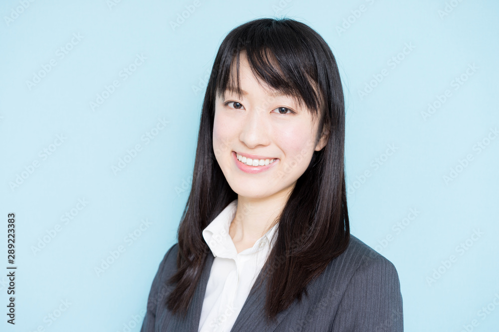 Young business woman wearing grey suit against light blue background Young business woman wearing grey suit against light blue background