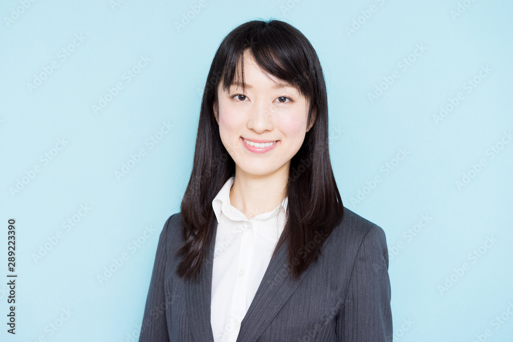 Young business woman wearing grey suit against light blue background Young business woman wearing grey suit against light blue background