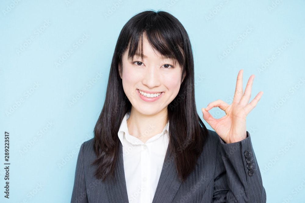 Young business woman showing OK sign against light blue background Young business woman showing OK sign against light blue background