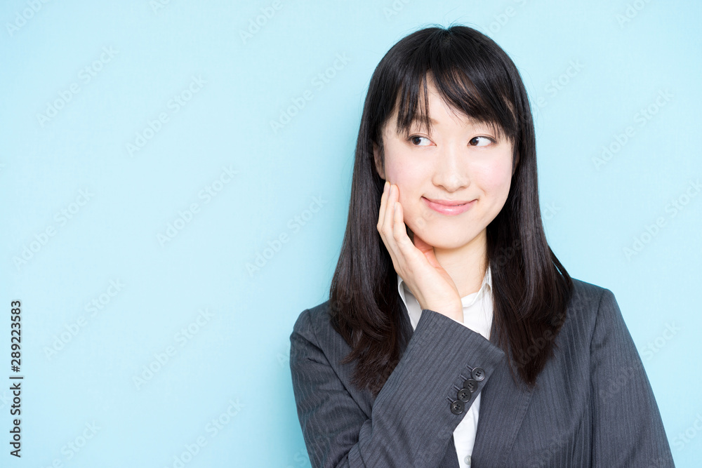 Young business woman thinking against light blue background Young business woman thinking against light blue background