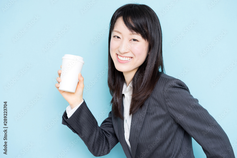 Young business woman holding coffee against light blue background Young business woman holding coffee against light blue background