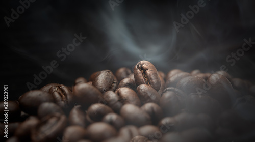 Aroma roasted coffee beans with smoke rising over dark background
