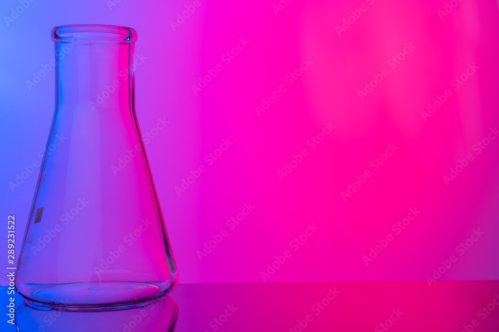 Chemical glassware close up on neon pink-purple background Chemical glassware close up on neon pink-purple background