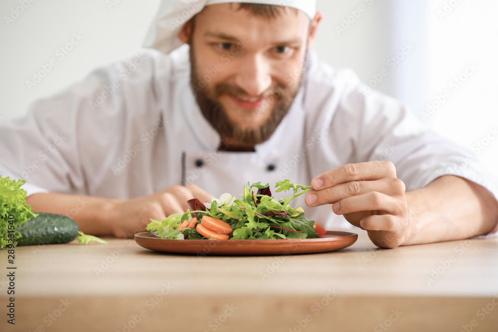 Handsome male chef with salad in kitchen