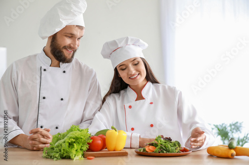 Professional chefs preparing vegetable salad in kitchen