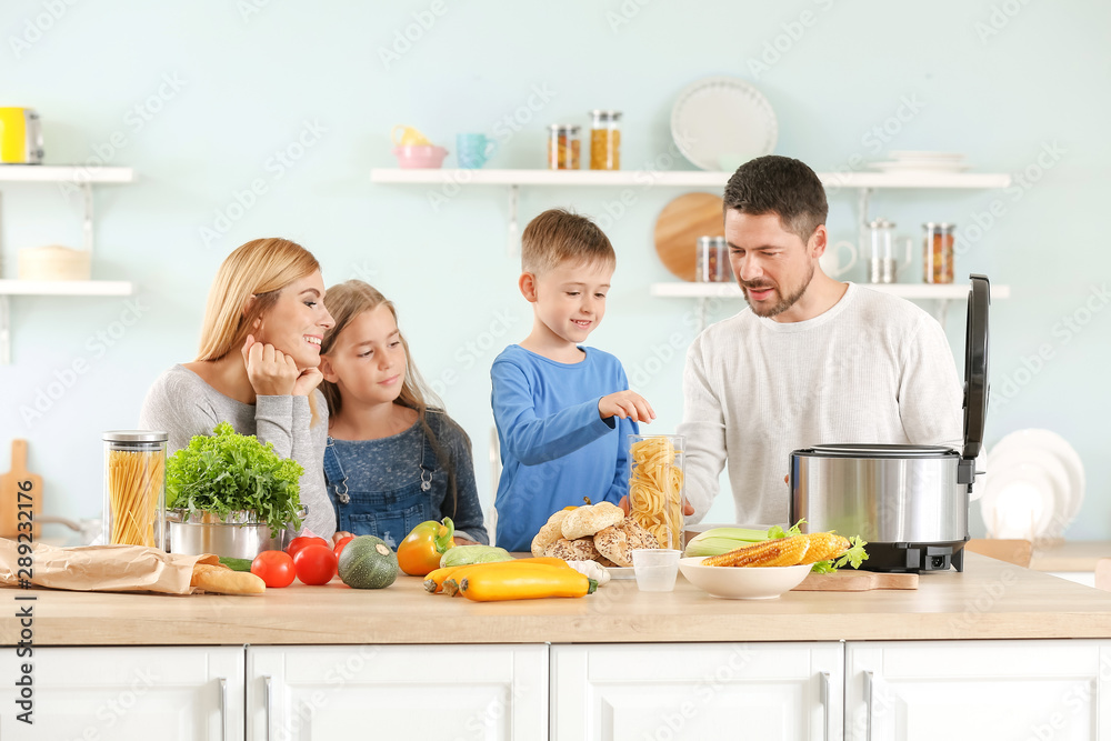 Happy family using modern multi cooker in kitchen Happy family using modern multi cooker in kitchen