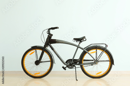 Modern bicycle near light color wall