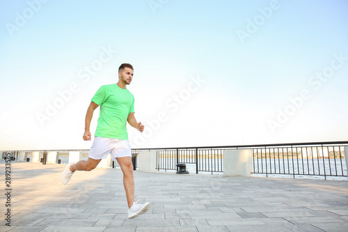 Handsome sporty man running near river