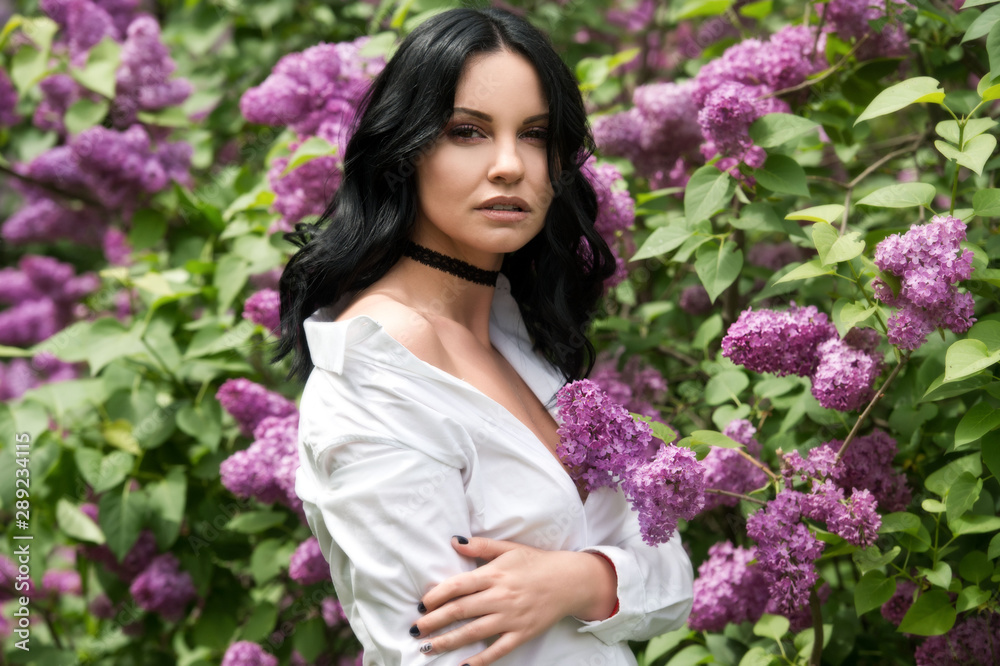 Beautiful woman in lilac garden.