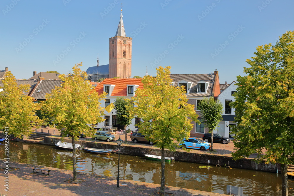 Historic houses located inside the fortified town of Naarden, Netherlands, with the clock tower of the Grote Kerk church in the background