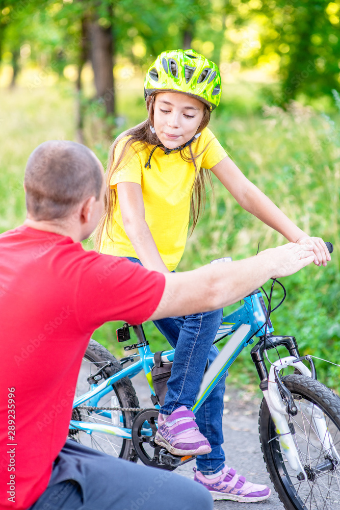 Father communicates with his daughter, teaching her how to ride a bicycle