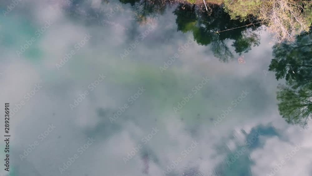 Aerial rising above pond with sky reflections in autumn park