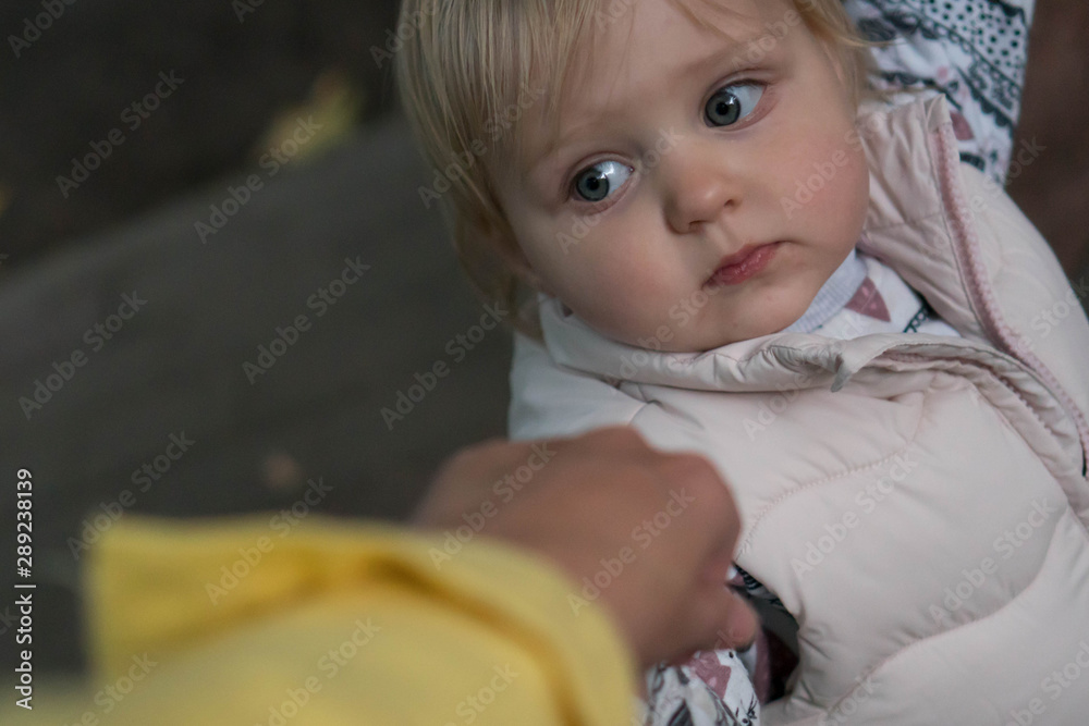 Fototapeta premium Toddler holds mom's hand and looks at her, close-up. Little cute girl holds the hand of an adult on a walk. joint walks with the child
