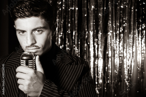 Photography Handsome latino man singing in front of vintage microphone in nightclub with sil