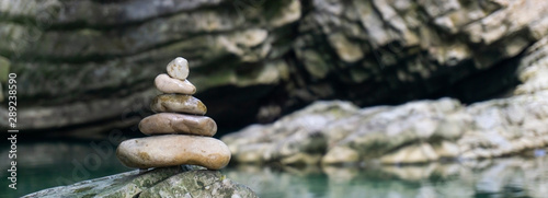 Harmony, balance and simplicity concept. A stone pyramid on the background of river water. Simple poise pebbles, rock zen sculpture