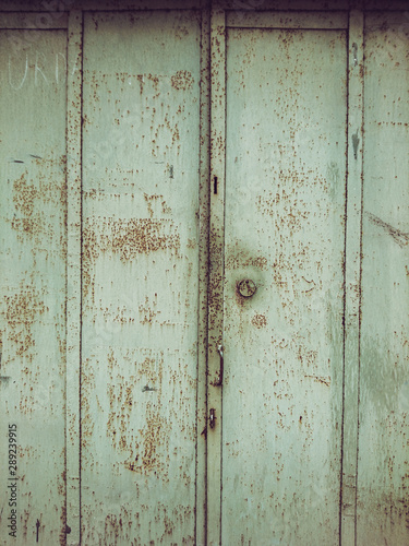 Background image of the green door of an old rusted garage