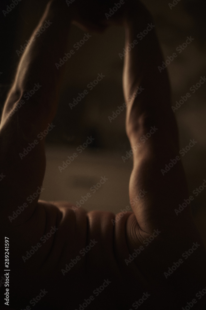 Authentic horizontal closeup shot of fit man. Strong male practicing yoga in dark intimate atmosphere, standing calm in asana. Film grain effect. Handsome athletic body in motion captured indoors Authentic horizontal closeup shot of fit man. Strong male practicing yoga in dark intimate atmosphere, standing calm in asana. Film grain effect. Handsome athletic body in motion captured indoors