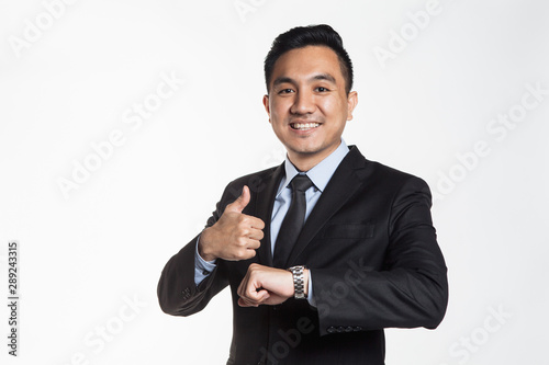 Man in business suit looking at his wrist watch while showing thumbs up
